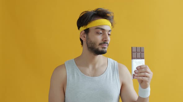 Portrait of Middle Eastern Man in Sportswear Saying No to Chocolate and Eating Apple