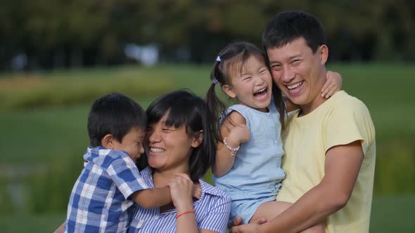 Excited Asian Family of Four Laughing in Park