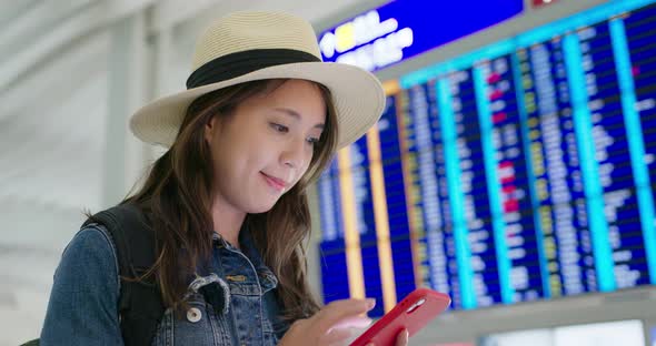 Woman check the flight schedule on cellphone in the airport