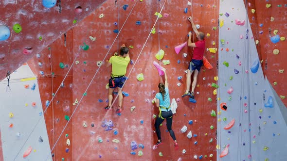 Men and woman practicing rock climbing in fitness studio 4k