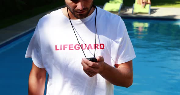 Lifeguard looking at stopwatch near the poolside