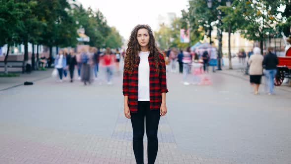 Zoom in Time-lapse of Beautiful Girl with Long Curly Hair Standing in Street Looking at Camera When