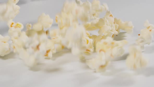 Fresh popcorn falling onto a white surface in slow motion