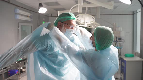 Doctors Team Help Wearing Medical Uniform To Each Other Prepare for Operation