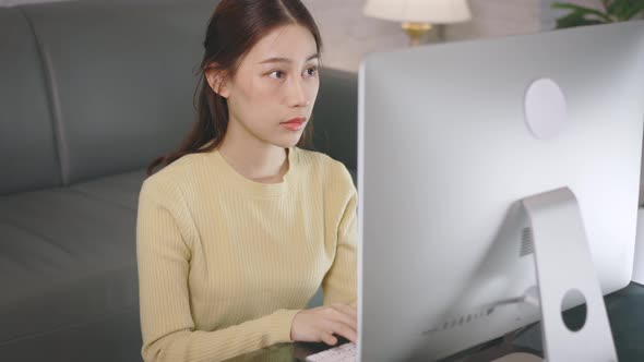 Young Asian Businesswoman Working From Home and Using Desktop Computer While Sitting in Living Room