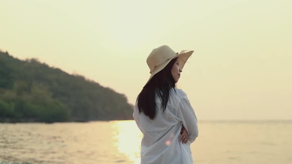 Attractive Asian woman feeling lonely while standing to look at view ocean beautiful sunset.