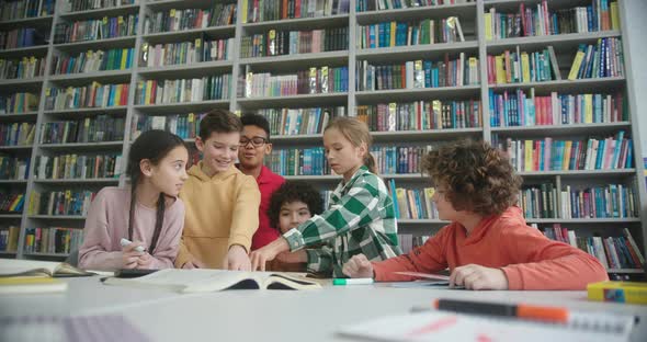 Kids Draw with Markers in Sketchbook at Table in Library