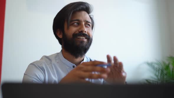 Closeup Lowangle View of Smiling Indian Businessman Explaining Project Details to Partner Sitting at