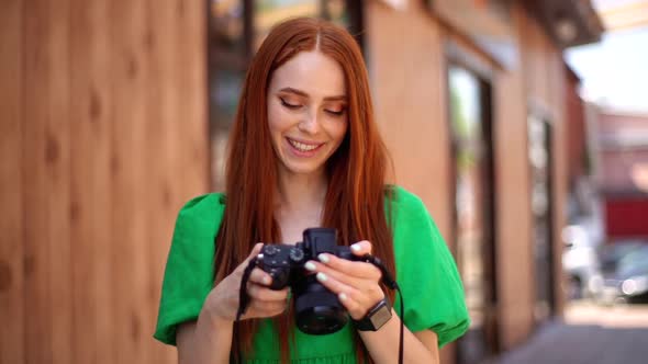 Front View of Laughing Young Woman Photographer Watching at Professional Camera Screen After Taking