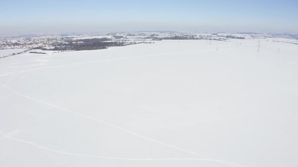Aerial Drone Shot  A White Snowcovered Field in Winter  a Townscape in the Background