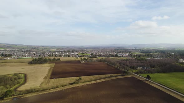 Aerial Drone flying towards Tractor Ploughing a field in Rural Perthshire, Scotland