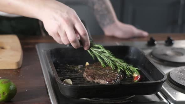 chef spreads sprig of rosemary on fresh piece of beef