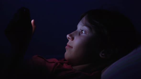 Kid Watching Video on Smartphone in Bed at Night