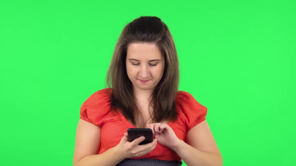 Portrait of Cute Girl Making Selfie on Mobile Phone Then Looking Photos. Green Screen