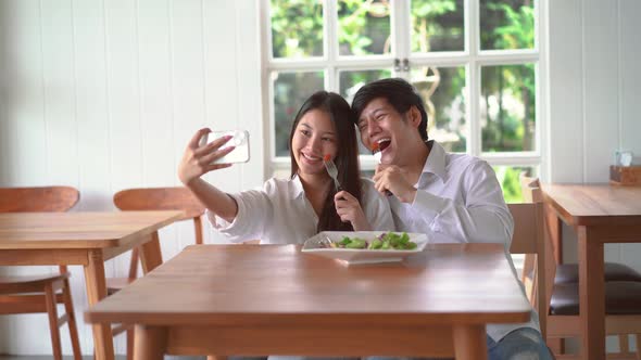 Happy couple posing taking selfie together use smartphone enjoying romantic date at restaurant