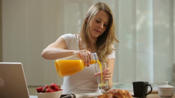 Woman having breakfast and using laptop computer