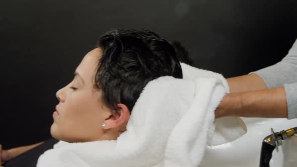 Hair stylist drying woman hair with towel