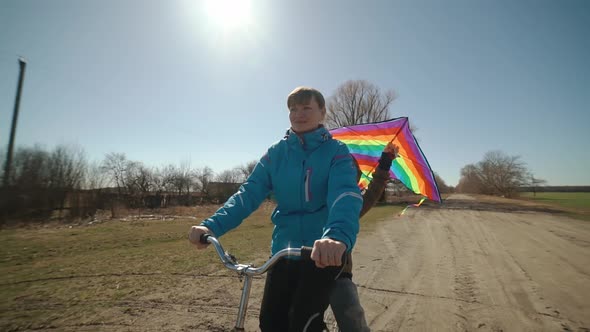 A Happy Mother Carries Her Son on a Bicycle Along the Road