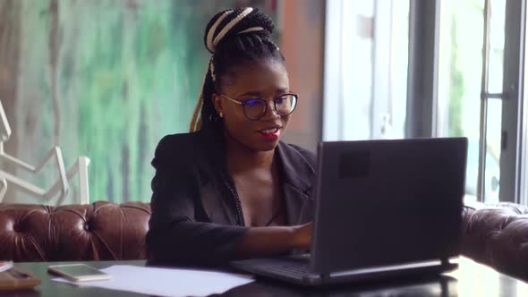 Young Black Woman Using Laptop Computer in Cafe. Female Professional Working with Notebook