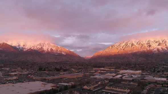 Aerial view flying backwards from snow capped mountains at sunset