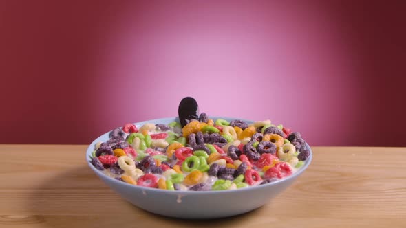 Spoon Falls Into Deep Bowl Filled with Multicolored Corn Rings and Milk