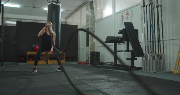 Attractive Woman Working Out with Battle Ropes in the Gym Intense Focused Woman Training Hard to