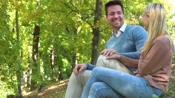 A Young Attractive Couple Talks and Laughs Together in a Park on a Sunny Day