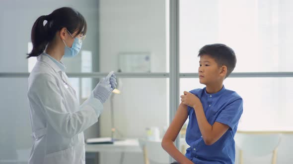 Doctor Vaccinating Asian Kid in Clinic