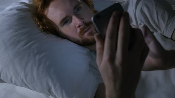 Man Using Smartphone in Bed at Night