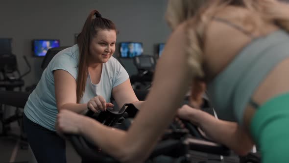 Two caucasian women ride a bikes at the gym. Shot with RED helium camera in 4K.