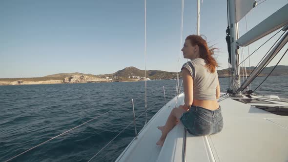 Beautiful Woman on a Yacht Enjoys the Journey on the Background of the Islands of Ibiza or Mallorca