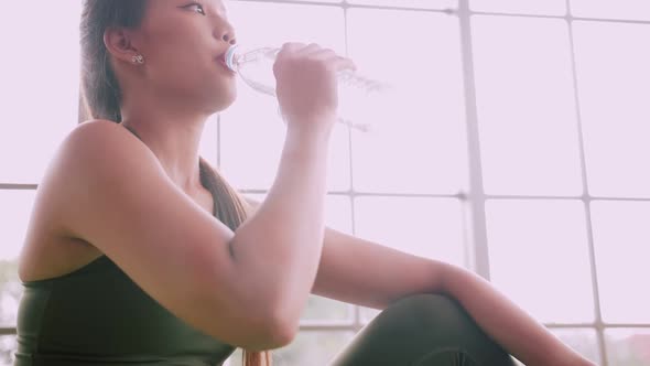 Asian girl drinking water after exercising at home.