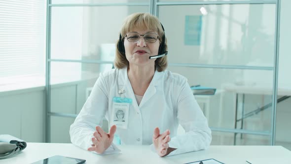 Senior Female Doctor in Headset Giving Online Consultation