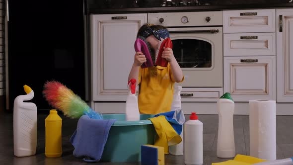 Cute Little Girl Playing with Brushes and Rags for Cleaning Sitting on the Floor