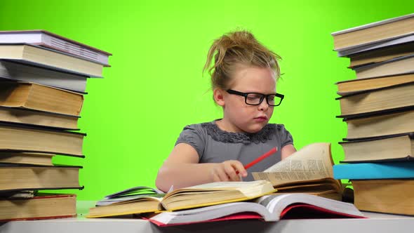 Little Girl Sitting at the Table and Nervously Throws Book. Green Screen