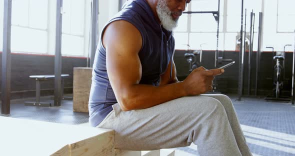 Senior man using smartphone in a gym 