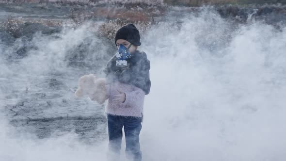 A Lost Child in Protective Mask Going in Clouds of Toxic Smoke. Girl Whith a Toy in the Hands.