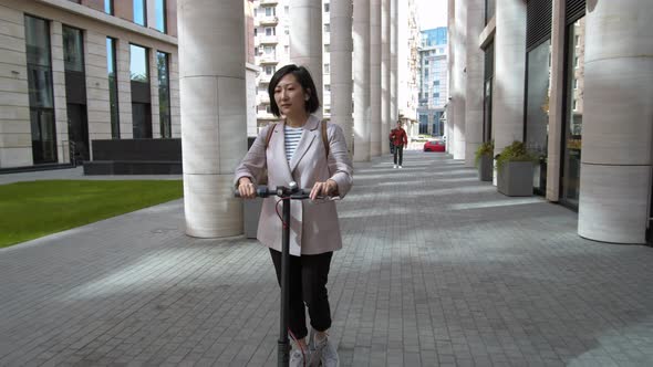 Woman Riding Electric Kick Scooter in Downtown