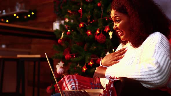 Brazilian Woman Connection with Her Family Online in Evening Room with Garlands Lights Backgroind