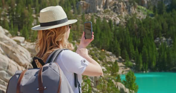 Traveler Woman Takes Pictures on Smartphone of Cinematic Green Lake. Adventure