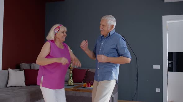 Happy Old Senior Couple Dancing Having Fun Celebrating Retirement Anniversary in Living Room at Home