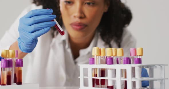 Video of biracial female doctor holding test tube on blue background