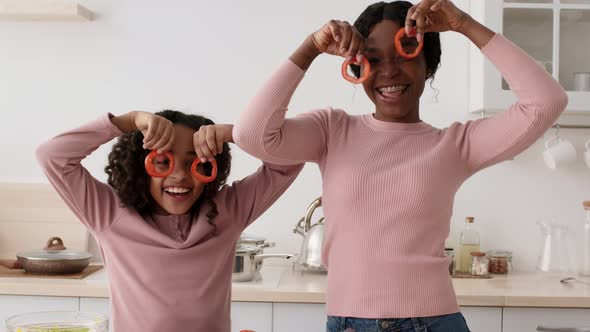 Cheerful African American Mother and Daughter Taking on Tomato Glasses and Dancing at Kitchen