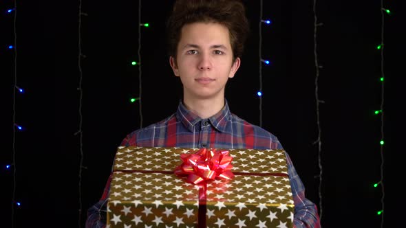 Boy with a Gift Box on Black Background. Gift Box with Ribbon for Happy New Year, Merry Christmas
