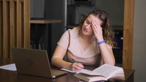 Woman is Sitting at Her Desk at Home and Has Headache