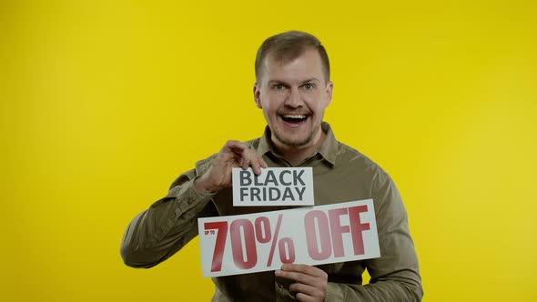 Shocked Amazed Store Client. Man Showing Black Friday and Up To 70 Percent Off Inscriptions Signs