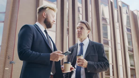 Confident businessman and his colleague in front of modern office building.