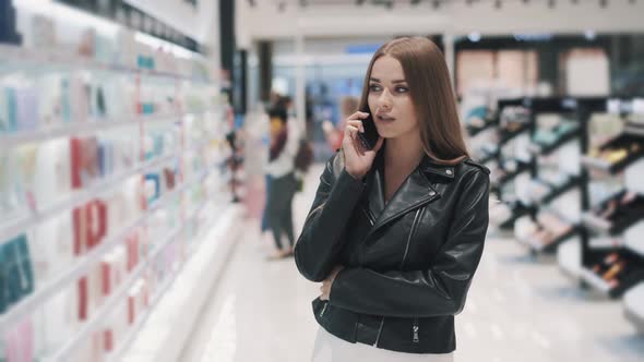 Young Woman Talking on Smartphones with Her Boyfriend While Shopping