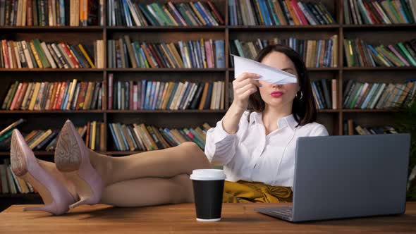 Joyful Secretary in Blouse and Skirt Plays with Paper Plane