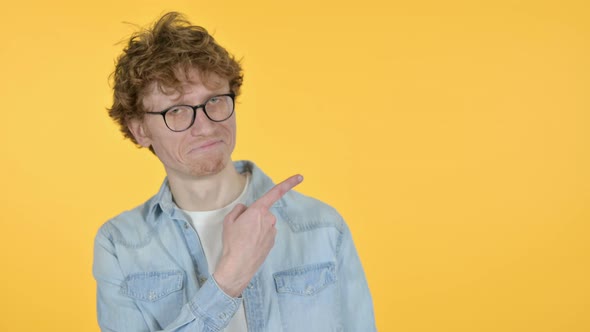 Copy Space, Redhead Young Man Pointing with Finger, Yellow Background